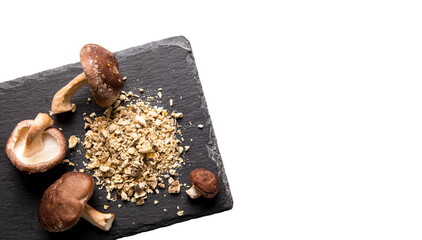 Flat lay view of dry powder made of shiitake mushrooms, Lentinula edodes. Food ingredient on black...