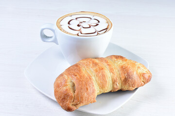 Cup of Colombian coffee, accompanied by baked bakery on white wooden background