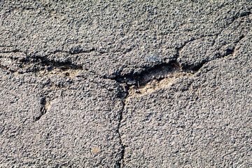 Cracked asphalt surface texture. Road or sidewalk pothole, broken pavement. Lack of timely repairing of infrastructure