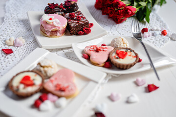beautiful tasty romantic selection of pink chocolate love heart shape cakes for wedding, mothers day,  valentines day, spring flower biscuits tartlet and rose petals 