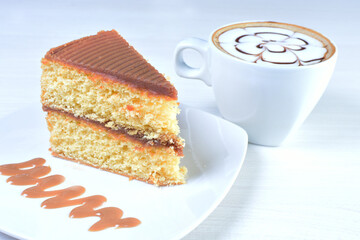 Cup of Colombian coffee, accompanied by baked cake on white wooden background