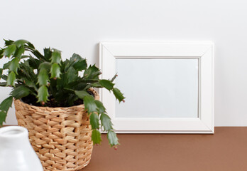 Front view of white poster frame mockup with  plant in a pot