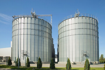 Modern granary. background A large agro-processing plant for the storage and processing of grain crops. Large metal barrels of grain. Granary elevator. Vertical image.