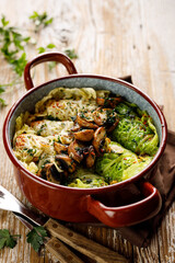 Traditional cabbage rolls stuffed with rice and mushrooms in an enamel dish on a wooden table, close up view
