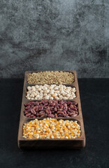 Wooden plates with raw beans and popcorn on a dark background