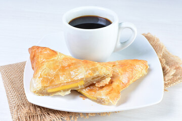 Cup of Colombian coffee, accompanied by baked bakery on white wooden background