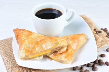 Cup of Colombian coffee, accompanied by baked bakery on white wooden background