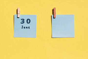 June 30st . Day of 30 month, calendar date. Two blue sheets for writing on a yellow background. Top view, copy space. Summer month, day of the year concept