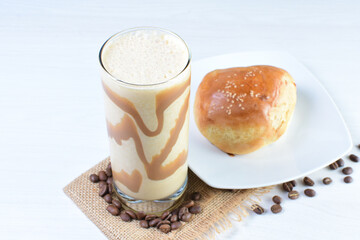 Colombian coffee milkshake, accompanied by baked bakery on white wooden background