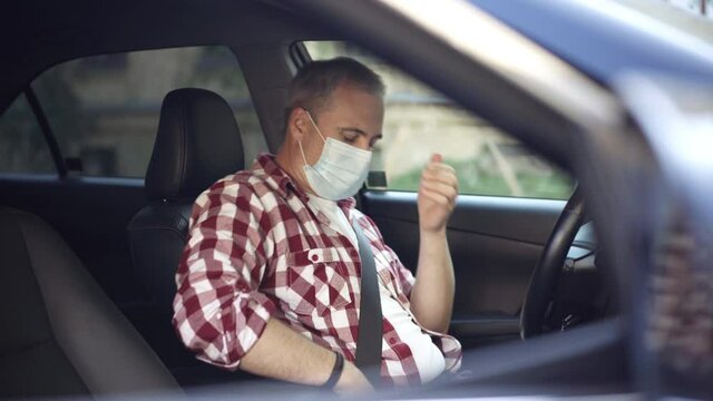Confident adult man putting on Covid-19 face mask and getting out of car. Side view middle shot of Caucasian guy taking safety measures on coronavirus pandemic outbreak. New normal lifestyle.