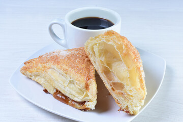 Cup of Colombian coffee, accompanied by baked bakery on white wooden background