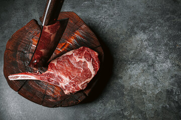 on a wooden block for meat a fresh raw tamahawk steak or a cowboy steak with a butcher's chopping...