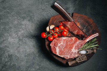 on a wooden block for meat a fresh raw tamahawk steak or a cowboy steak with a butcher's chopping...