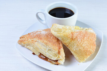 Cup of Colombian coffee, accompanied by baked bakery on white wooden background