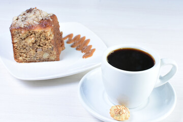 Cup of Colombian coffee, accompanied by baked cake on white wooden background