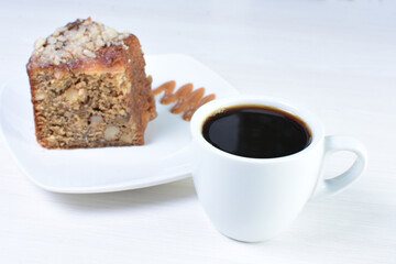 Cup of Colombian coffee, accompanied by baked cake on white wooden background