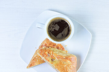 Cup of Colombian coffee, accompanied by baked bakery on white wooden background