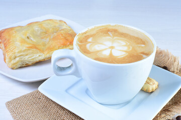 Cup of Colombian coffee, accompanied by baked bakery on white wooden background