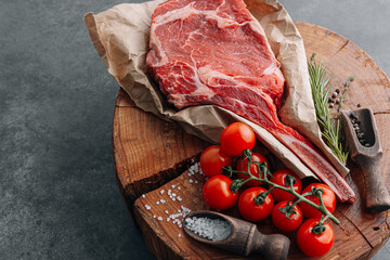 fresh raw cowboy tomahawk steak on a round wooden cutting board for meat