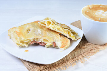 Cup of Colombian coffee, accompanied by baked bakery on white wooden background