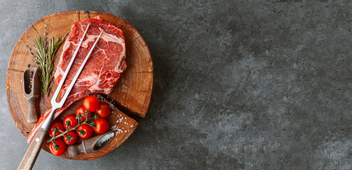 fresh raw cowboy tomahawk steak on a round wooden cutting board for meat