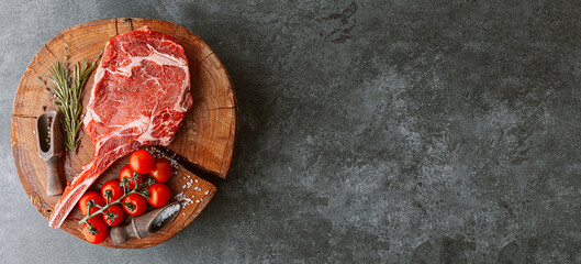 fresh raw cowboy tomahawk steak on a round wooden cutting board for meat