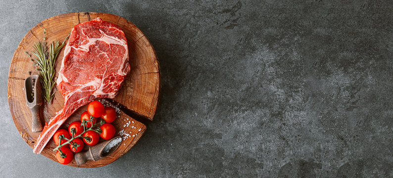 Fresh Raw Cowboy Tomahawk Steak On A Round Wooden Cutting Board For Meat