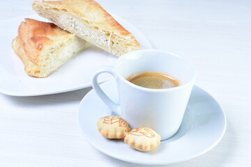 Cup of Colombian coffee, accompanied by baked bakery on white wooden background
