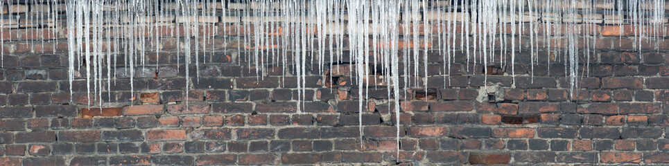 large group of icicles on brick wall background