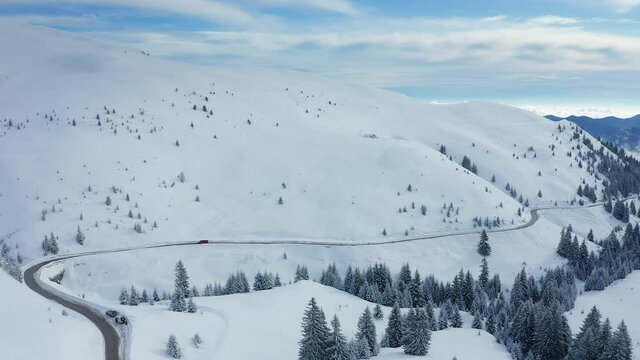 4K Aerial view of the winding road Transbucegi through Bucegi Mountains during a winter day in Romania