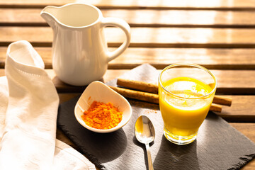 relaxing breakfast on a wooden table with golden milk with curcuma and cinnamon ingredients
