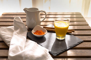 selective focus of a breakfast with the traditional Indian drink turmeric milk, which is a golden milk with cinnamon on a wooden table
