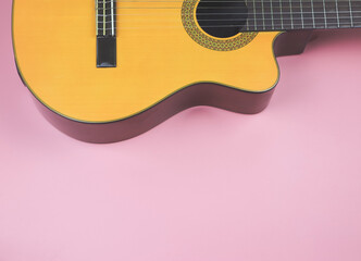  flat lay of acoustic guitar on pink background with copy space.