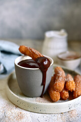 Traditional spanish dessert churros - fried choux pastry with chocolate sauce.