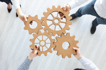 Group of business people stacking wooden gears top view - obrazy, fototapety, plakaty