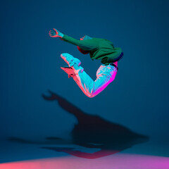 Flying. Stylish sportive boy dancing hip-hop in stylish clothes on colorful background at dance...