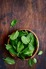 Fresh organic spinach leaves in a wooden bowl . Top view with copy space.