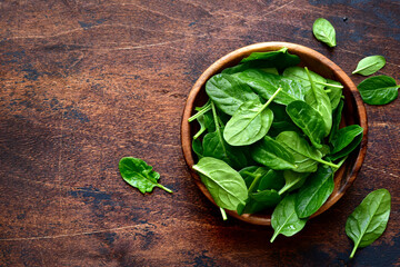 Fresh organic spinach leaves in a wooden bowl . Top view with copy space.