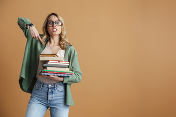 Shocked beautiful woman holding and pointing finger at books and planners