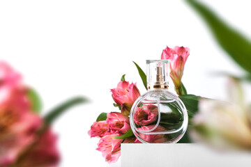 Glass perfume bottle on white podium. Floral arrangement. Minimal mockup style, soft focus, low...