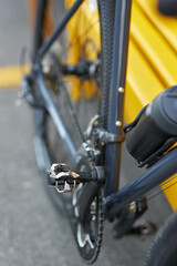 Close up shot of steel pedal of mountain bike parked near yellow bench outdoors