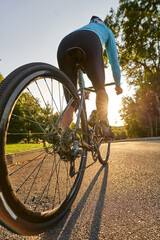 Low angle view of professional male bicycle racer riding his road bike in the park at sunset