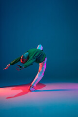 Fototapeta na wymiar Fashion. Stylish sportive boy dancing hip-hop in stylish clothes on colorful background at dance hall in neon light. Youth culture, movement, style and fashion, action. Fashionable bright portrait.