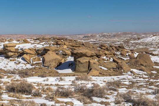 Interesting rock formations sitting in open snow covered desert in rural New Mexico on clear day