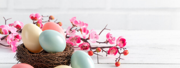 Close up of colorful Easter eggs in the nest with pink plum flower.