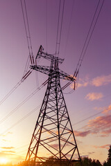 A silhouette of high voltage power lines against a colorful sky at sunrise.