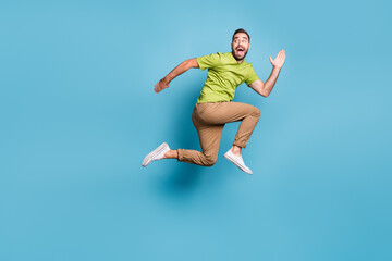 Full length profile side photo of young man jump up run empty space look back isolated on pastel blue color background