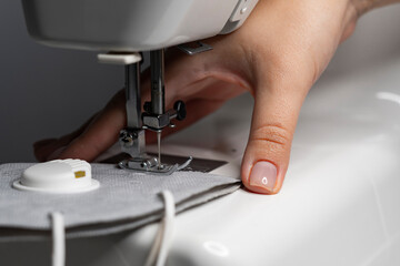 A woman sews a protective mask N95 