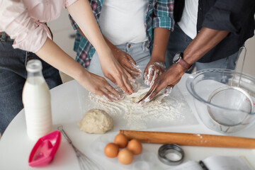 Obraz na płótnie Canvas Close up top cropped view of hands of multiethnic parents teaching their mixed race daughter to knead the dough