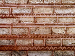 Texture of a brick wall decorated with a pattern. Background of the old dirty wall outdoors